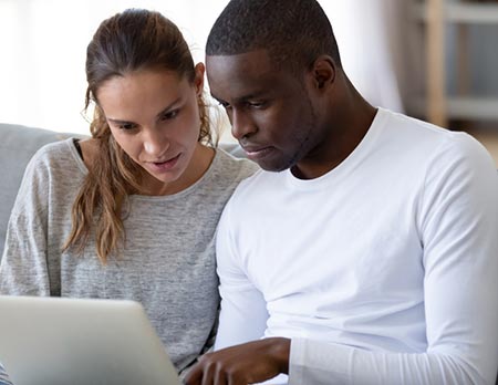 Bi-Racial couple contacting their computer