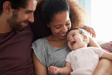 Bi-Racial couple enjoy giggles with their adopted baby