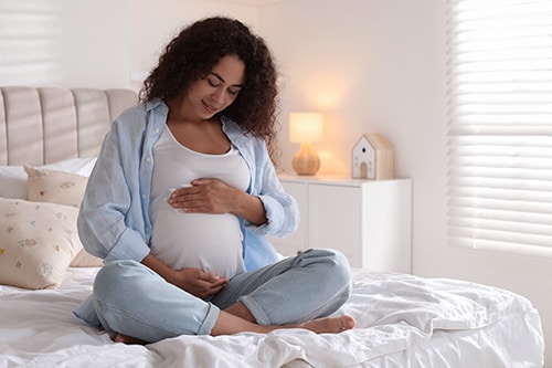 A pregnant mother seated on her bed, one of many birth parents seeking adoptive families