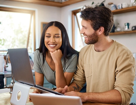 Happy bi-racial couple learning about domestic adoption online