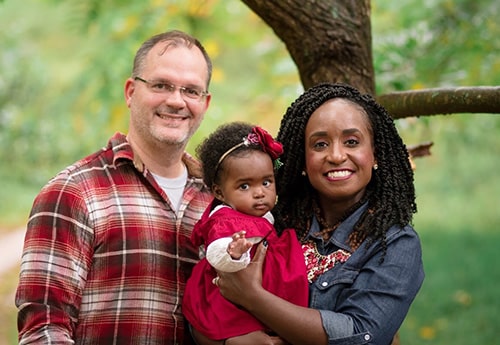 Todd and Anna with their adopted daughter outdoors